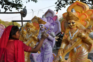 An artist putting finishing touches to idol of goddess Saraswati