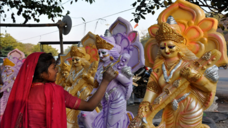 An artist putting finishing touches to idol of goddess Saraswati