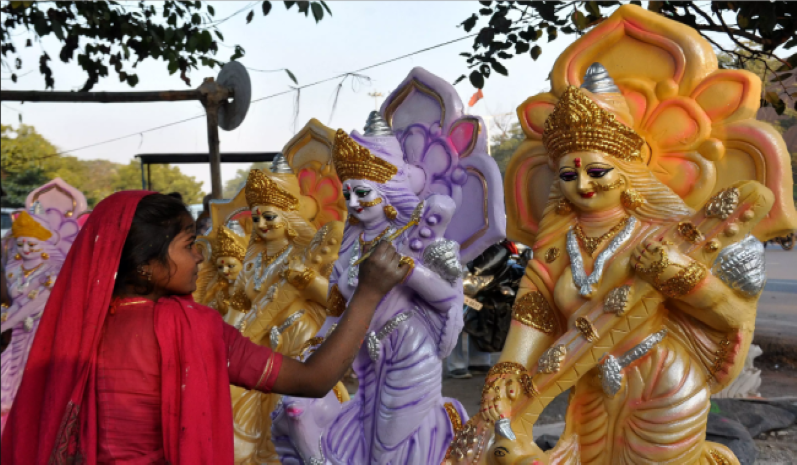 An artist putting finishing touches to idol of goddess Saraswati